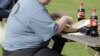 FILE - An overweight man eats his lunch on a park bench. Obesity has become a growing problem worldwide. 