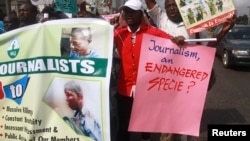 FILE - Journalists hold placards as they protest along a road days after a journalist was assaulted by mortuary attendants at the Lagos State University Teaching Hospital, in Lagos, Aug. 16, 2012. 