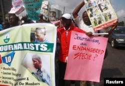 FILE - Journalists hold placards as they protest along a road days after a journalist was assaulted by mortuary attendants at the Lagos State University Teaching Hospital, in Lagos, Aug. 16, 2012.