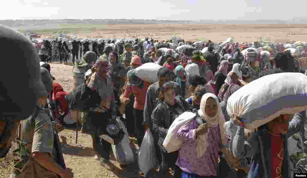 Turkish soldiers stand guard as Syrian Kurds cross the border fence into Turkey near the southeastern town of Suruc in Sanliurfa province, Sept. 19, 2014. 