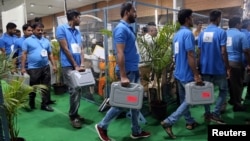 Election staff members carry electronic voting machines (EVM) at a vote counting center in Mumbai, India, May 23, 2019. 