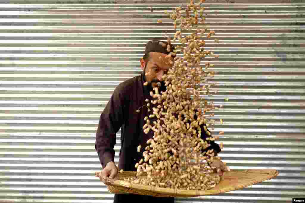 A man cleans peanuts for sale outside a shop in Peshawar, Pakistan.