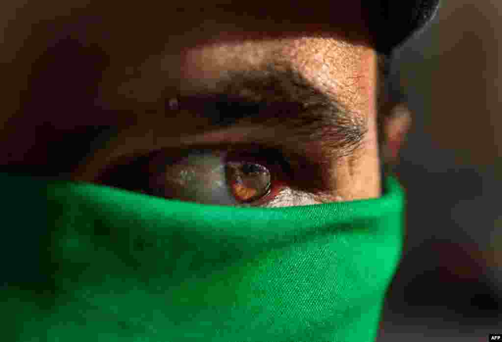March 29: In Tripoli, a pro Gadhafi supporter wears a green scarf on his face. (AP Photo/Jerome Delay)