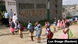 Murid-murid mengenakan masker berdiri berbaris di depan sekolah Merlan Paillet di Abidjan, Pantai Gading 25 Mei 2020. (Foto: Luc Gnago/Reuters)