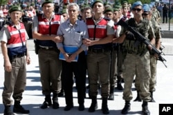 Paramilitary police and members of the special forces escort former Air Force commander Akin Ozturk and other suspects of last year's failed coup, outside the courthouse at the start of a trial, in Ankara, Turkey, Tuesday, Aug. 1, 2017.