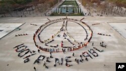 FILE - In this Dec. 6, 2015 file photo, environmentalist activists form a human chain representing the peace sign and the spelling out "100% renewable", on the side line of the COP21, United Nations Climate Change Conference near the Eiffel Tower in Paris
