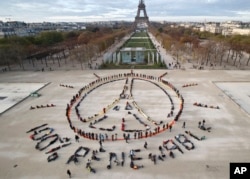 FILE - In this Dec. 6, 2015 file photo, environmentalist activists form a human chain representing the peace sign and the spelling out "100% renewable", on the side line of the COP21, United Nations Climate Change Conference near the Eiffel Tower in Paris
