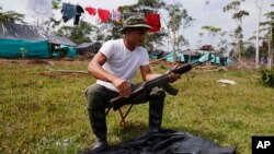 Un rebelde de las Fuerzas Armadas Revolucionarias de Colombia, FARC, limpia su arma en un campamento en La Carmelita, cerca de Puerto Asia en el suroccidental departamento colombiano de Putumayo, el 28 de febrero, de 2017.