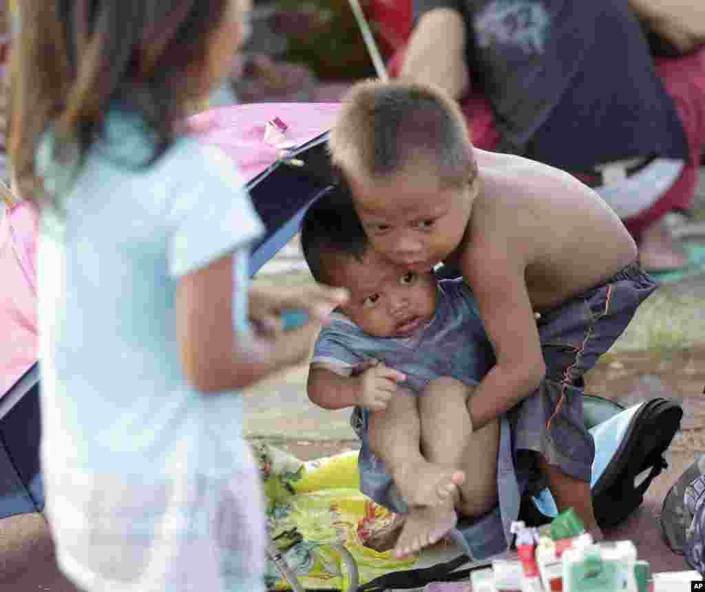 A boy carries his brother as they camp out at a stadium to flee the fighting between government forces and Muslim rebels in Zamboanga city in southern Philippines.