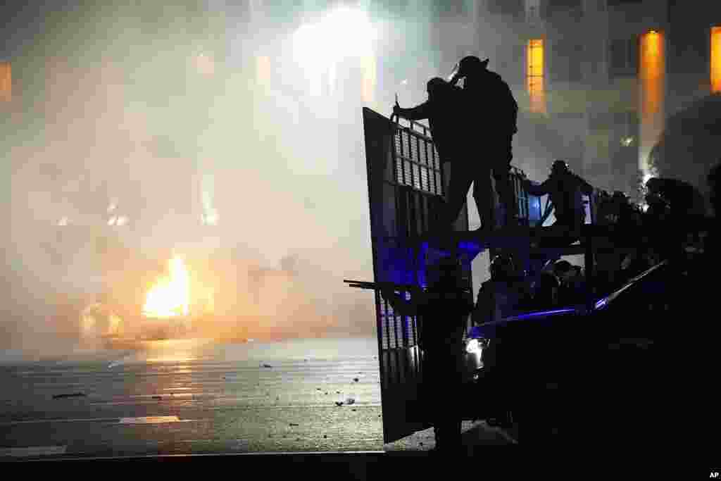 A police car burns as riot police prepare to stop protesters in the center of Almaty, Kazakhstan, Jan. 5, 2022. Demonstrators denouncing the doubling of prices for liquefied gas have clashed with police in Kazakhstan's largest city and held protests in about a dozen other cities in the country.