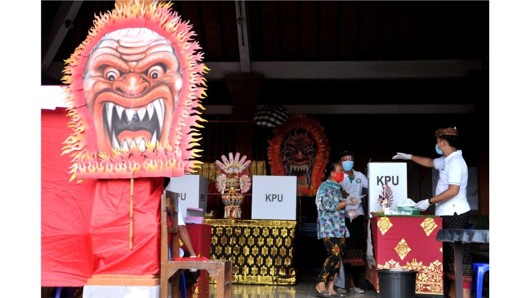 Seorang perempuan memakai masker saat Pilkada di Badung, Provinsi Bali, 9 Desember 2020 di tengah pandemi Covid. (Foto: Antara/Fikri Yusuf via REUTERS)