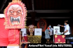 Seorang perempuan memakai masker saat Pilkada di Badung, Provinsi Bali, 9 Desember 2020 di tengah pandemi Covid. (Foto: Antara/Fikri Yusuf via REUTERS)