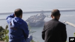 South Koreans on a hilltop park watch the U.S. nuclear-powered aircraft carrier USS Nimitz at Busan port, south of Seoul, South Korea, May 11, 2013. 
