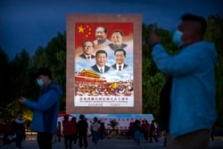 Pengunjung mengambil foto di alun-alun umum di dasar Istana Potala dekat mural besar yang menggambarkan para pemimpin China di Lhasa. (Foto: AP)