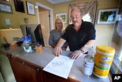 In this Wednesday, June 10, 2020, photo, Cod Cove Inn owners Ted and Jill Hugger show a draft of a compliance form that inn owners may be required to have out-of-state guests sign before being allowed to check in at their inn in Edgecomb, Maine.