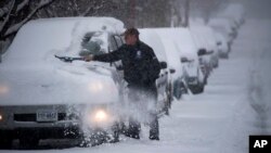 눈폭풍이 발생한 버지니아 로아노크의 거리에서 남성이 자신의 차에 쌓인 눈을 치우고 있다. 