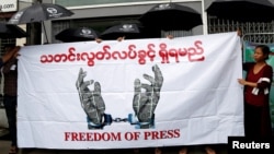 FILE - Journalists hold a banner as they protest against a law they say curbs free speech in Yangon, Myanmar, June 8, 2017.
