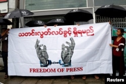 FILE - Journalists hold a banner as they protest against a law they say curbs free speech in Yangon, Myanmar, June 8, 2017.