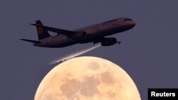 An airplane of German air carrier Lufthansa passes the moon over Frankfurt, Germany, April 9, 2017. 