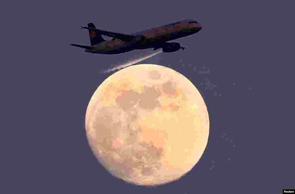 An airplane of German air carrier Lufthansa passes the moon over Frankfurt, Germany, April 9, 2017.