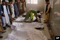 지난해 6월 아프가니스탄 헤라트에서 발생한 폭탄 테러로 사망한 희생자들의 사체가 인근 병원으로 이송된 가운데, 유가족들이 시신을 확인하고 있다.