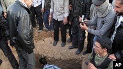 A Free Syrian Army fighter sits next to the grave of a comrade during the funeral for four people killed in a raid by government forces in a neighborhood of Damascus, Syria, April 5, 2012.