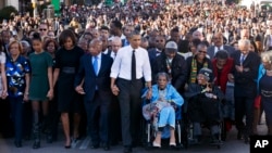 Presiden AS Barack Obama (tengah) bergandengan tangan dengan Amelia Boynton Robinson, yang dipukuli dalam tragedi "Minggu Berdarah" dalam peringatan 50 tahun pawai hak sipil di Selma, Alabama (7/3). (AP/Jacquelyn Martin)