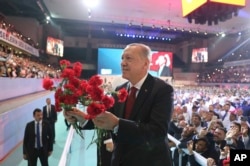 Turkey's President Recep Tayyip Erdogan throws flowers to his supporters as he arrives to deliver a speech at his ruling Justice and Development Party (AKP) congress in Ankara, Aug. 18, 2018.