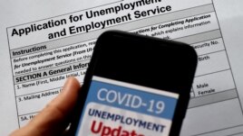 FILE - In this photo illustration, a COVID-19 Unemployment Assistance Updates logo is displayed on a smartphone on top of an application for unemployment benefits on May 8, 2020, in Arlington, Virginia.