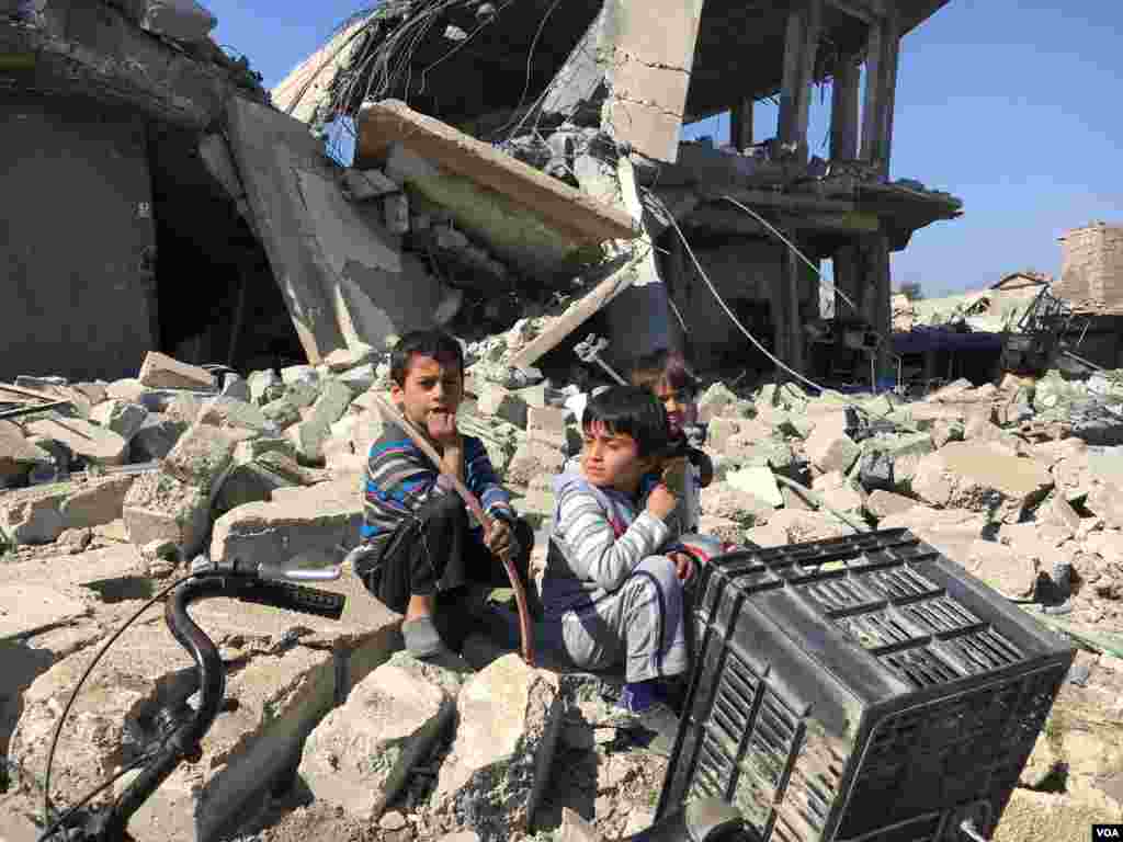 Children sit near a ruined building in Simoud , Mosul, Iraq, March 10, 2017. (K. Omer/VOA)