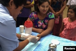 FILE - A public health worker takes a blood sample from a woman to be tested for malaria in Bo Rai district, Trat province, Thailand, Nov. 29, 2017.