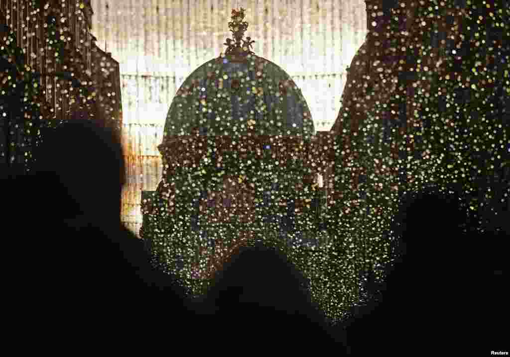 Visitors walk past Christmas lights towards Hofburg Palace's Michaeler Cupola in Vienna, Austria.