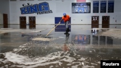 Darius Moses works removing water from the gymnasium at C.E. King High School following the aftermath of tropical storm Harvey in Houston, Texas, Sept. 8, 2017.