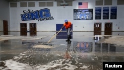 FILE - Darius Moses works removing water from the gymnasium at C.E. King High School following the aftermath of tropical storm Harvey in Houston, Texas, Sept. 8, 2017.