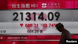 A man walks past a panel displaying the benchmark Hang Seng index during afternoon trading in Hong Kong, China, Jan. 4, 2016. 