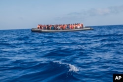 FILE - A rubber boat with 129 migrants on board, among them 60 women, is seen sailing out of control about 15 miles north of Al Khums, Libya, Aug. 1, 2017.