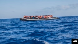 A rubber boat with 129 migrants on board, among them 60 women, is seen sailing out of control about 15 miles north of Al Khums, Libya, Aug. 1, 2017.