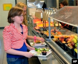 Clara Zonis, front, and Kelsey Hiscock select food items from the lunch line of the cafeteria at Draper Middle School in Rotterdam, N.Y. (AP Photo/Hans Pennink, File)