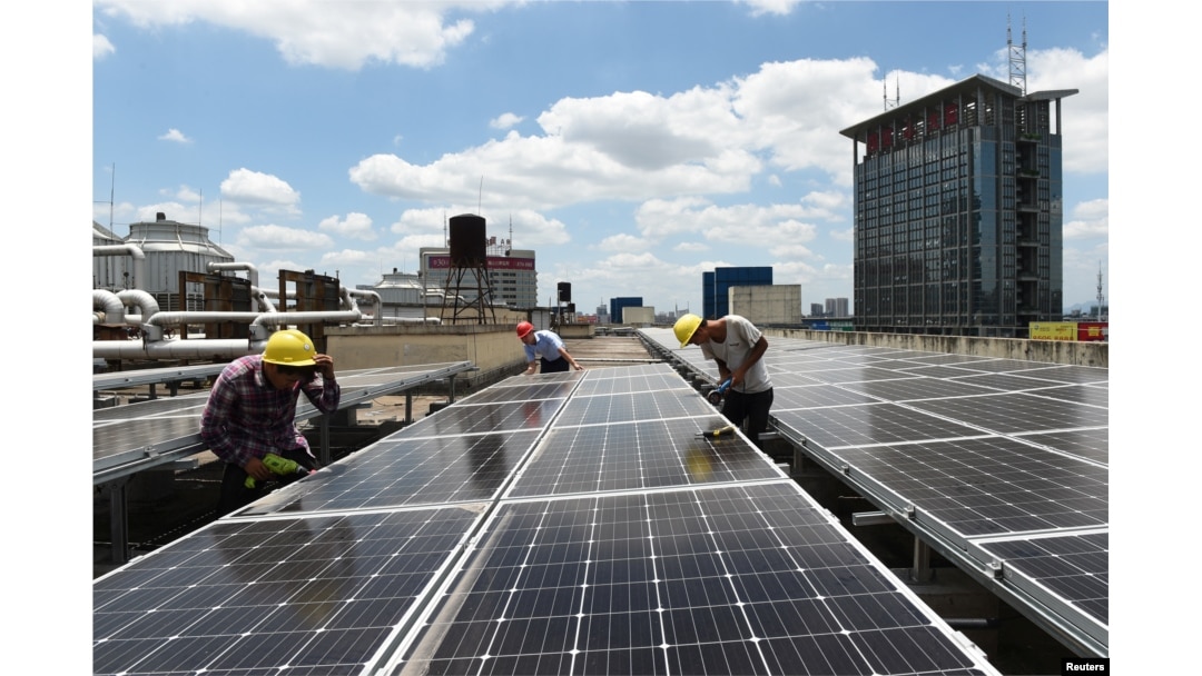 FILE - Employees install solar panels at a roof of Yiwu International Trade City in Yiwu, Zhejiang province, China, July 17, 2017.