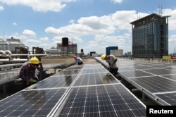 在中國浙江省義烏市國際商貿城的屋頂，工人安裝太陽能電池板（2017年7月17日)。