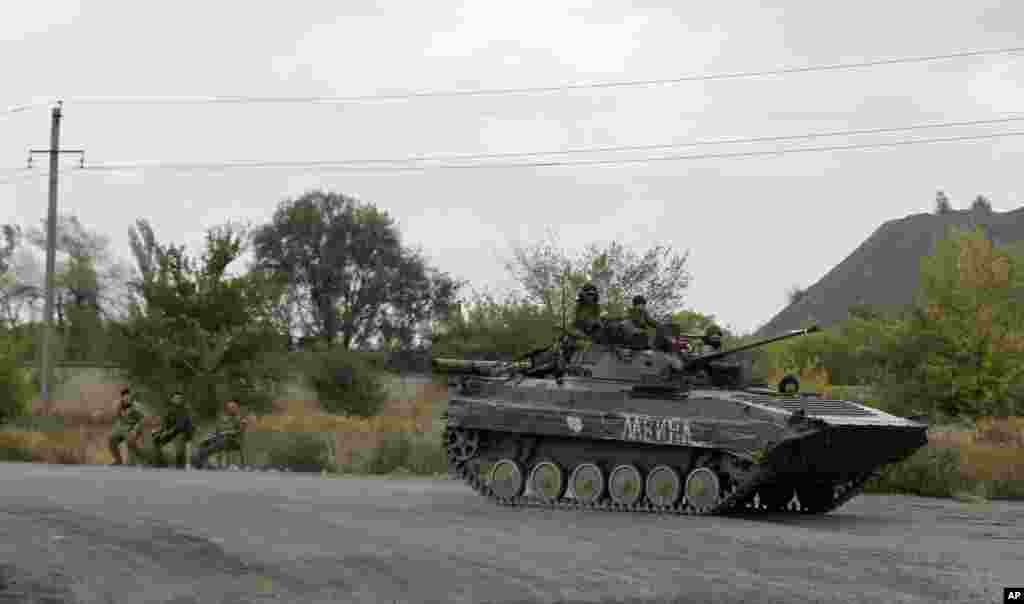 Pro-Russian gunmen sit atop an armored personal carrier at the checkpoint near Zhdanivka, eastern Ukraine, Sept. 23, 2014.