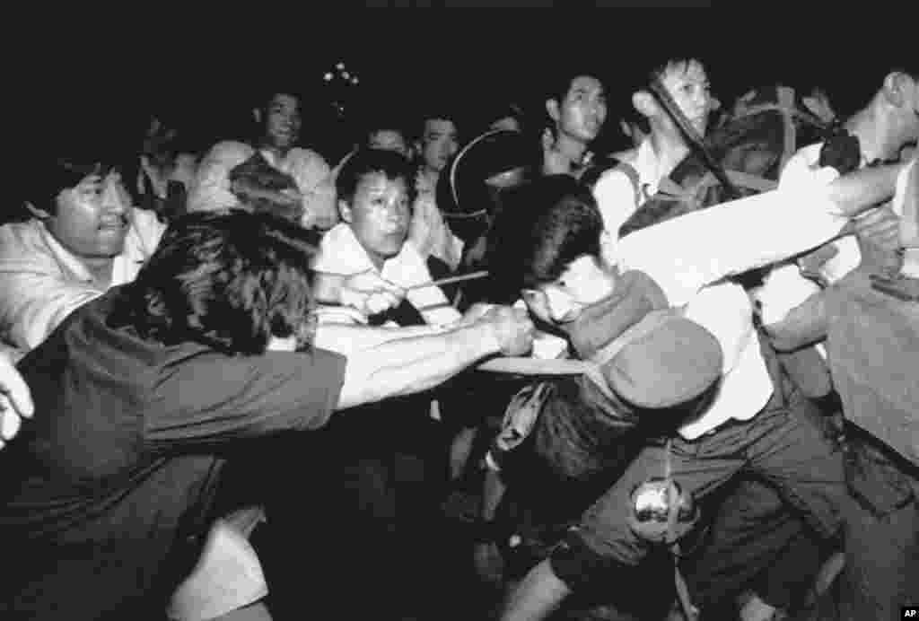 A man tries to pull a Chinese soldier away from his comrades as thousands of Beijing citizens turned out to block thousands of troops on their way towards Tiananmen Square, June 3, 1989. 