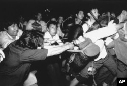 FILE - A man tries to pull a Chinese soldier away from his comrades as thousands of Beijing citizens turned out to block thousands of troops on their way towards Tiananmen Square, June 3, 1989.