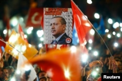 FILE - People wave flags and hold a portrait of Turkish President Recep Tayyip Erdogan as they celebrate the ruling AK Party's election win, in Ankara, Turkey Nov. 2, 2015.