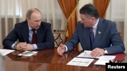 Russian President Vladimir Putin (L) talks to Federation Council Deputy Chairman Yuri Vorobyov during a meeting with members of the Federation Council at the Novo-Ogaryovo state residence outside Moscow, March 27, 2014.