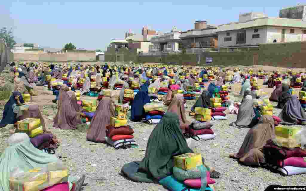Afghan burqa-clad women sit after they received ration aid in Kandahar.
