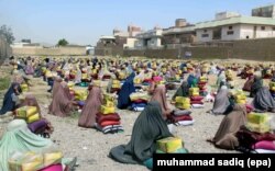 FILE - Afghan burqa clad women sit after they received ration aid in Kandahar, Afghanistan, 04 May 2016.