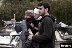 Residents help an injured man to walk after what activists said were three consecutive air strikes carried out by the Russian air force, the last which hit an ambulance, in the rebel-controlled area of Maaret al-Numan town in Idlib province, Syria, Jan. 1