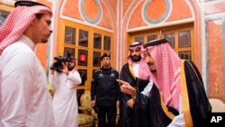 In this photo released by Saudi Press Agency, SPA, Saudi King Salman, right, points to Salah, a son, of Jamal Khashoggi as Crown Prince Mohammed bin Salman, second right, looks on, in Riyadh, Saudi Arabia, Oct. 23, 2018. 