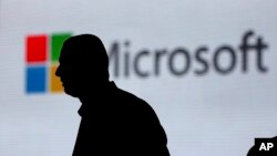 FILE - A man is silhouetted as he walks in front of a Microsoft logo at an event in New Delhi, India, Nov. 7, 2017. Microsoft says it’s uncovered new Russian hacking attempts targeting U.S. political groups ahead of midterm elections in November.